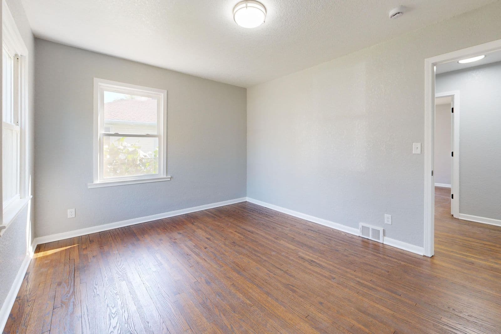After: Bright room with smooth white walls and hardwood floor
